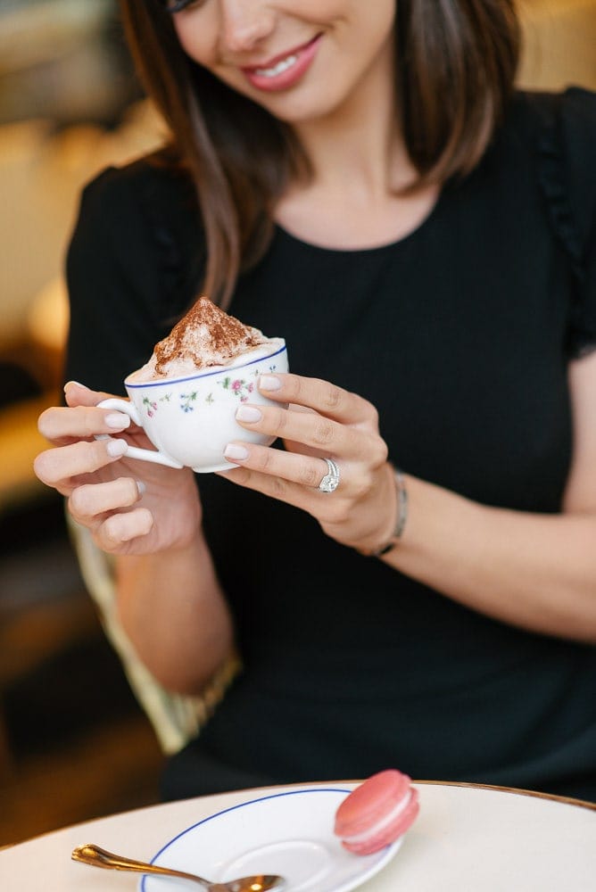 Beautiful girl holding cappuccino in her hands and showing her diamond ring