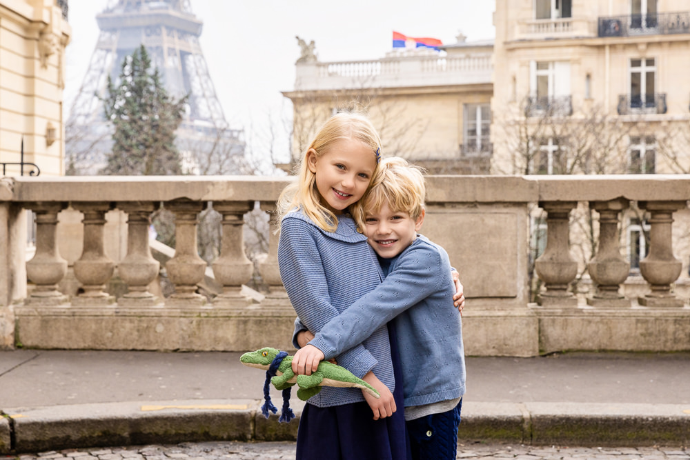 Cute girl and boy dressed in blue hugging for a family pictures in Paris