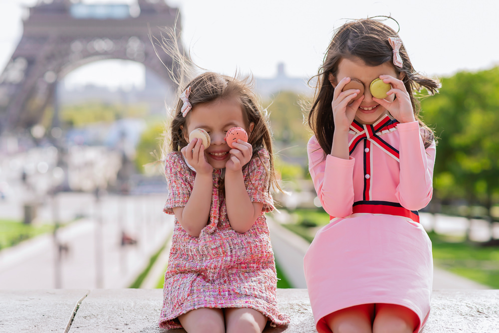 Cute kids posing for fun family photos with colorful macarons by the Eiffel Tower