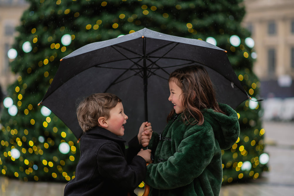Kids playing with umbrella in front of Christmas tree in Place Vendome