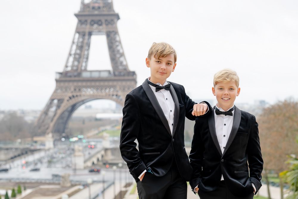 Two boys dressed in tuxedos posing for professional photos in Paris by the Eiffel Tower