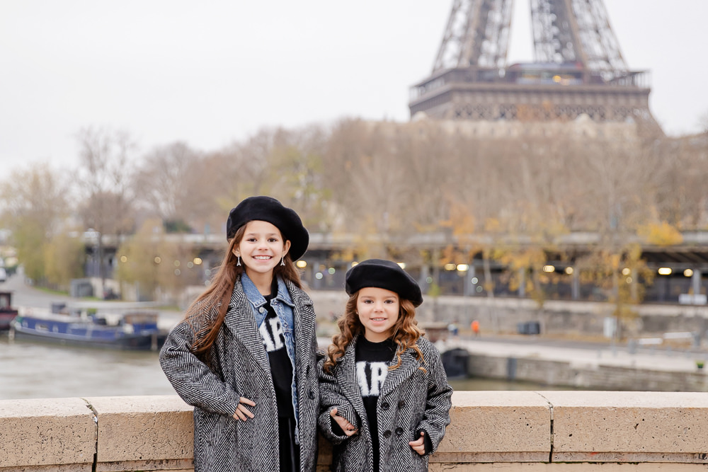 two cute girls wearing french berets and eiffel tower earrings posing for professional photos in Paris